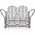 Four clear ribbed glass spice jars with perforated lids arranged in a silver-colour metal rack on white background