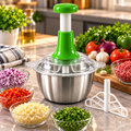 Green press-handle manual food chopper with clear lid and stainless steel bowl in a kitchen setting